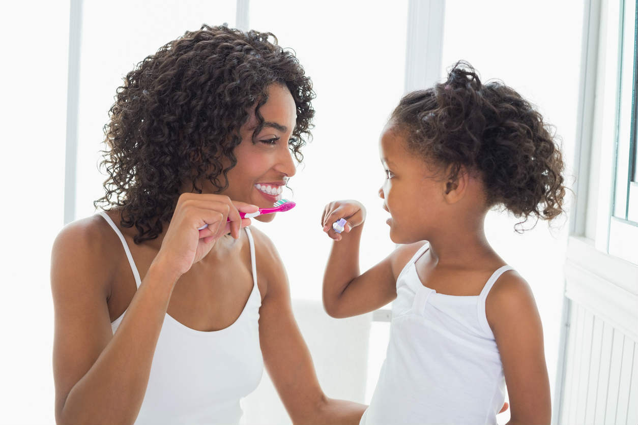 mother teaching daughter to brush teeth